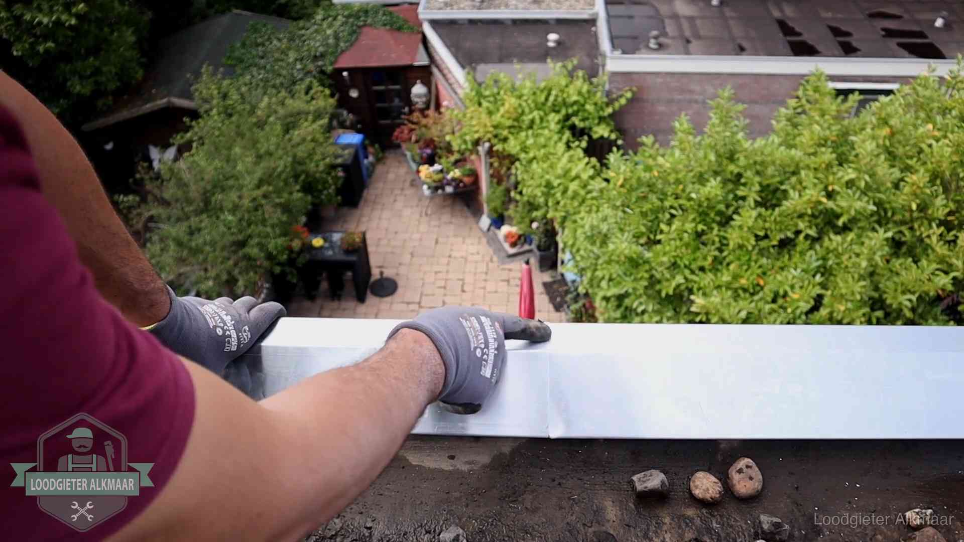 Vakman plaatst een daktrim op de dakrand van een woning in Alkmaar