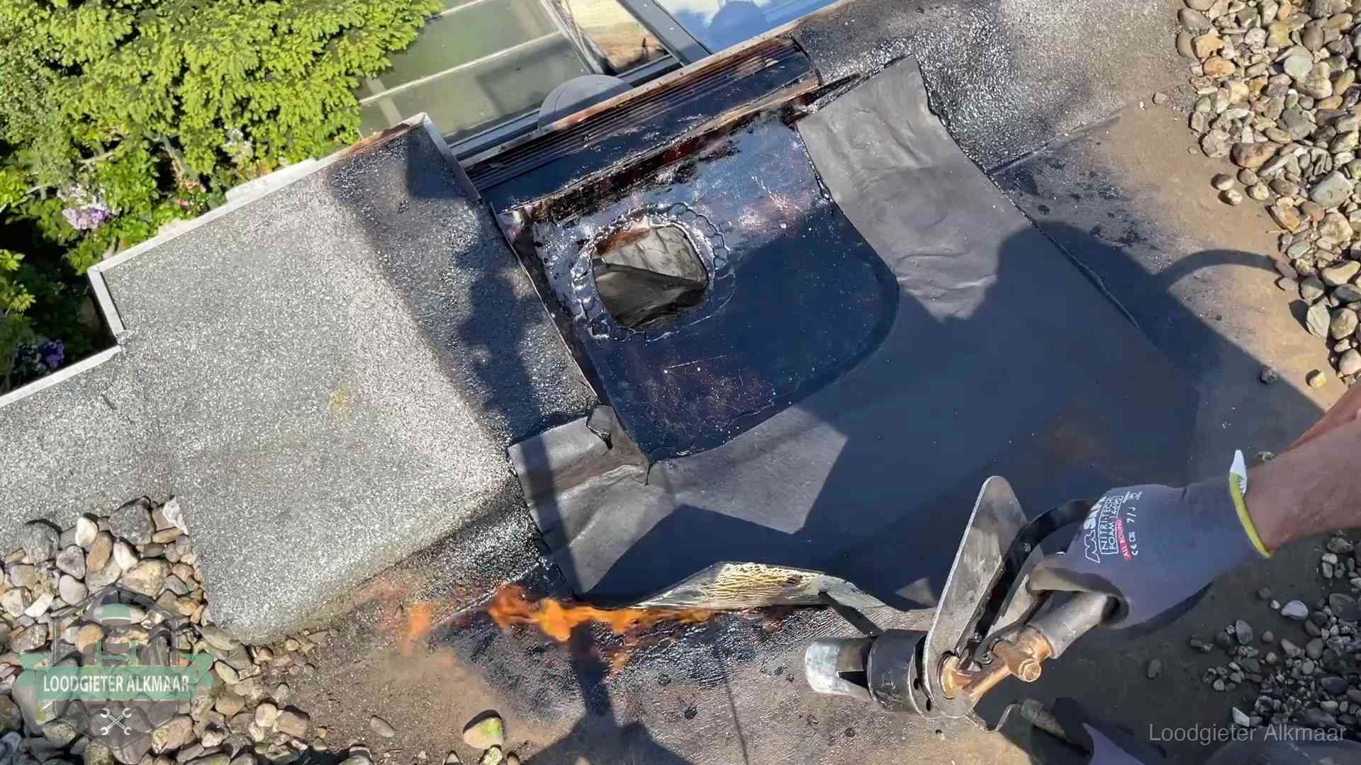 Dakdekker brandt bitumen rond een doorvoer tijdens een daklekkage-reparatie in Alkmaar