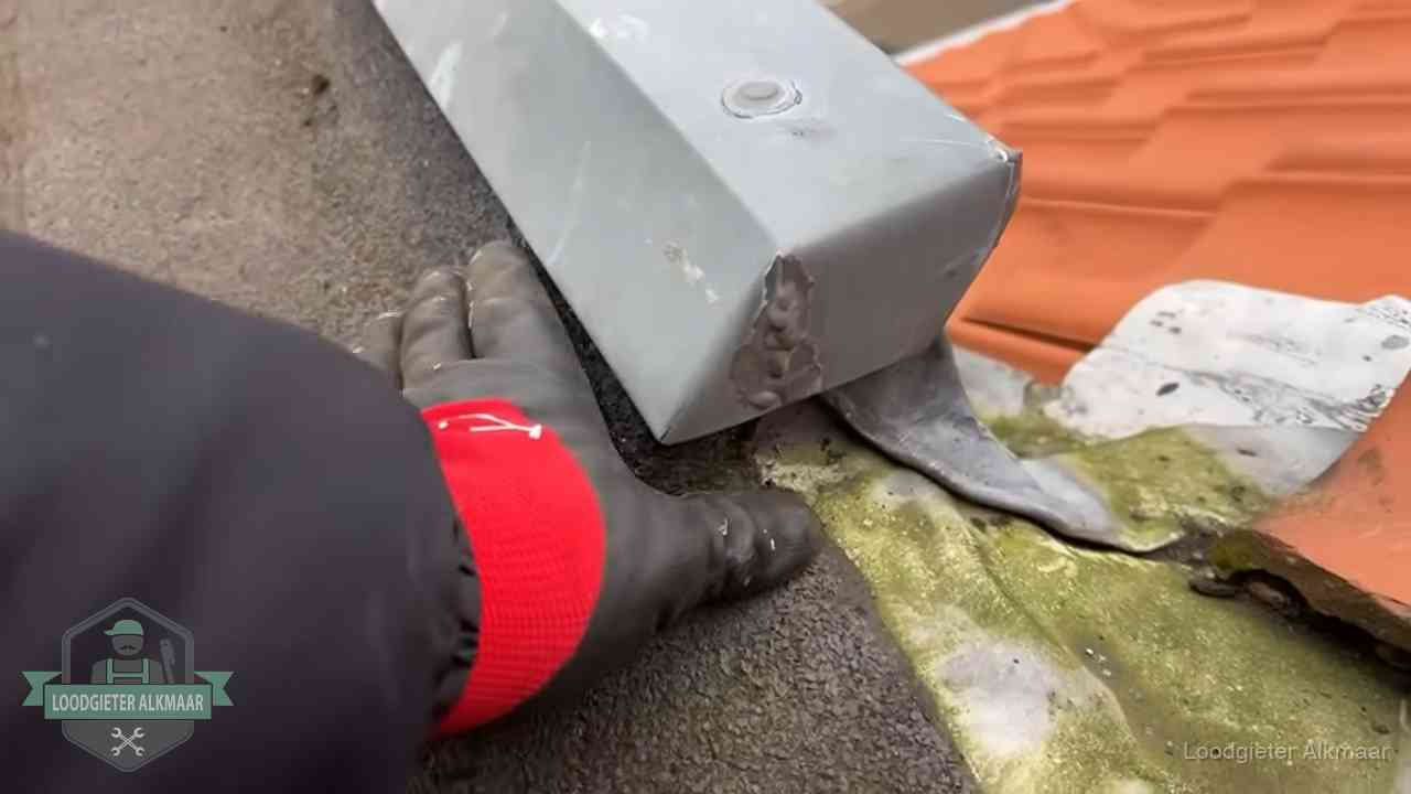 Controle van een zinken hemelwaterafvoer met loodslab bij dakpannen in Alkmaar