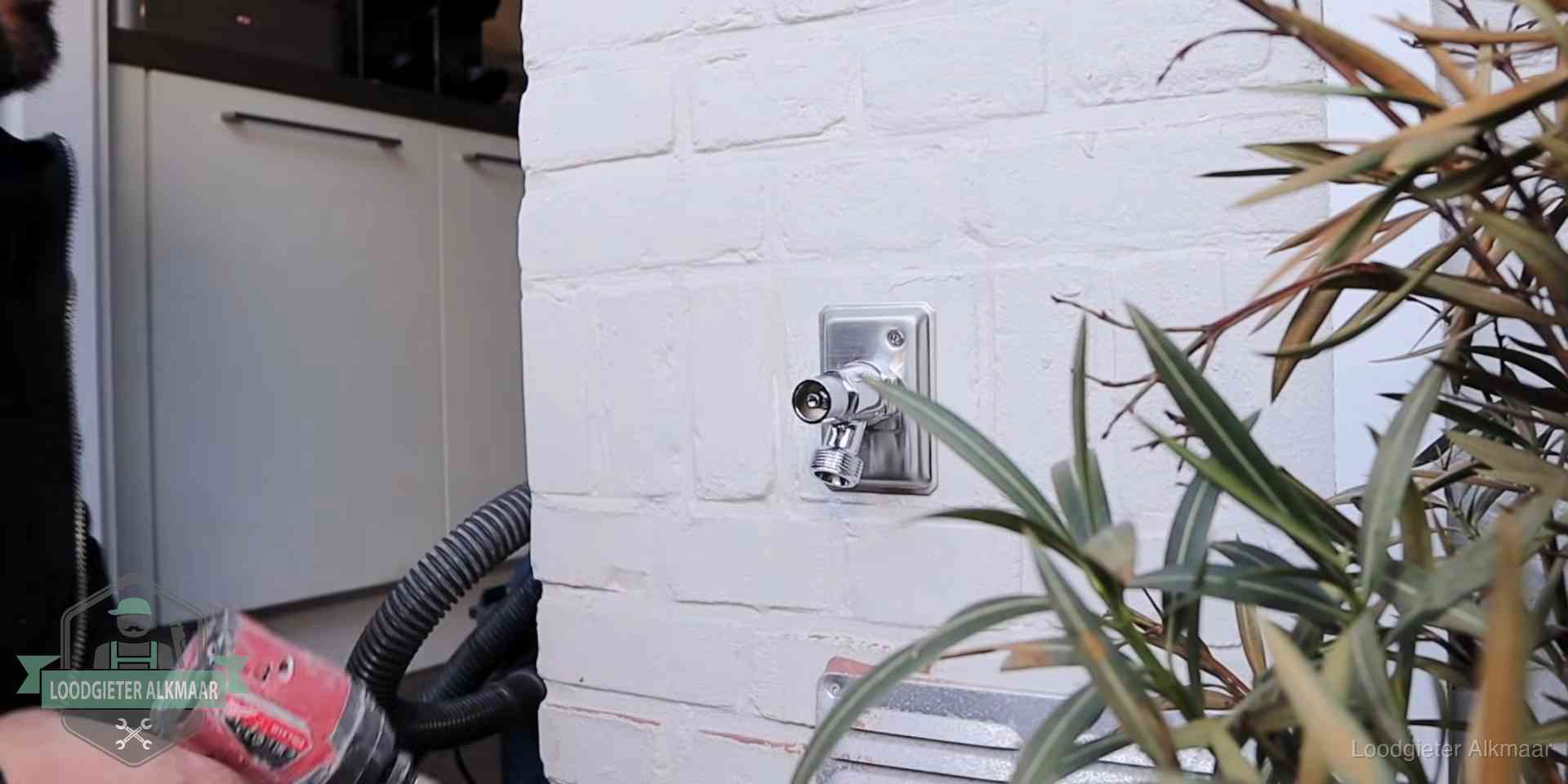 Chromen kraan op een muurplaat bij een woning in Alkmaar, dichtdraaien is stap een van de lektest