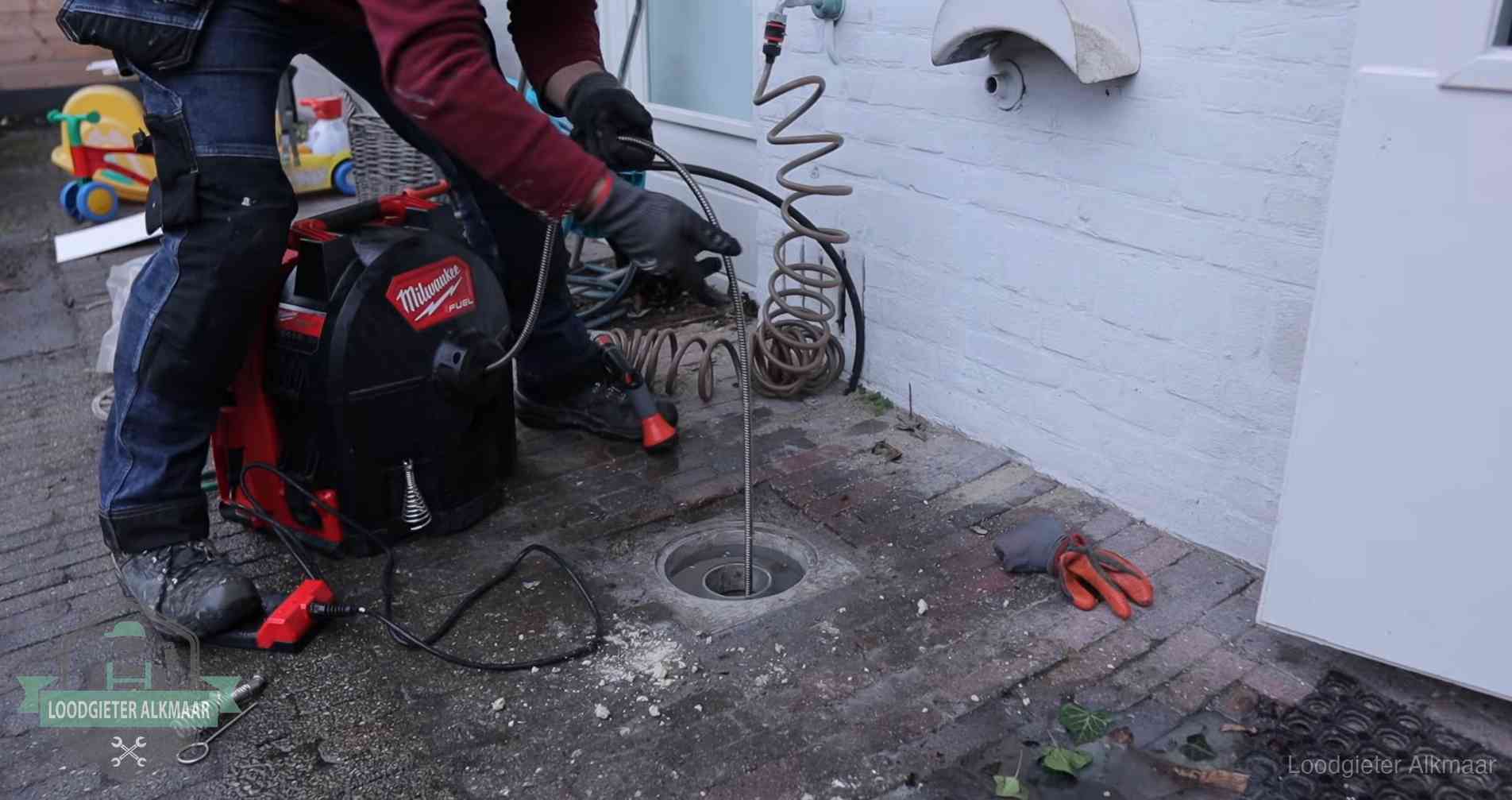Erfgrens en gemeenteriool in Alkmaar Ontstoppingsputje in de bestrating naast de gevel van een woning in Alkmaar