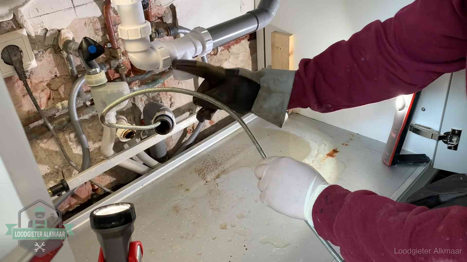Spiraal of hogedruk in Alkmaar Ontstoppingsveer gaat in een geopende sifonaansluiting onder het aanrecht in Alkmaar