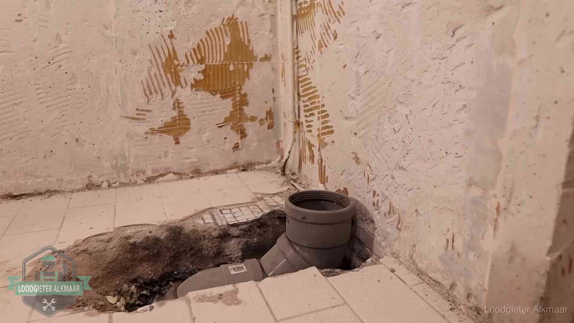 Verzakt riool herstellen in Alkmaar Opengebroken vloer met een nieuwe pvc-rioolbocht in een gegraven sleuf in Alkmaar