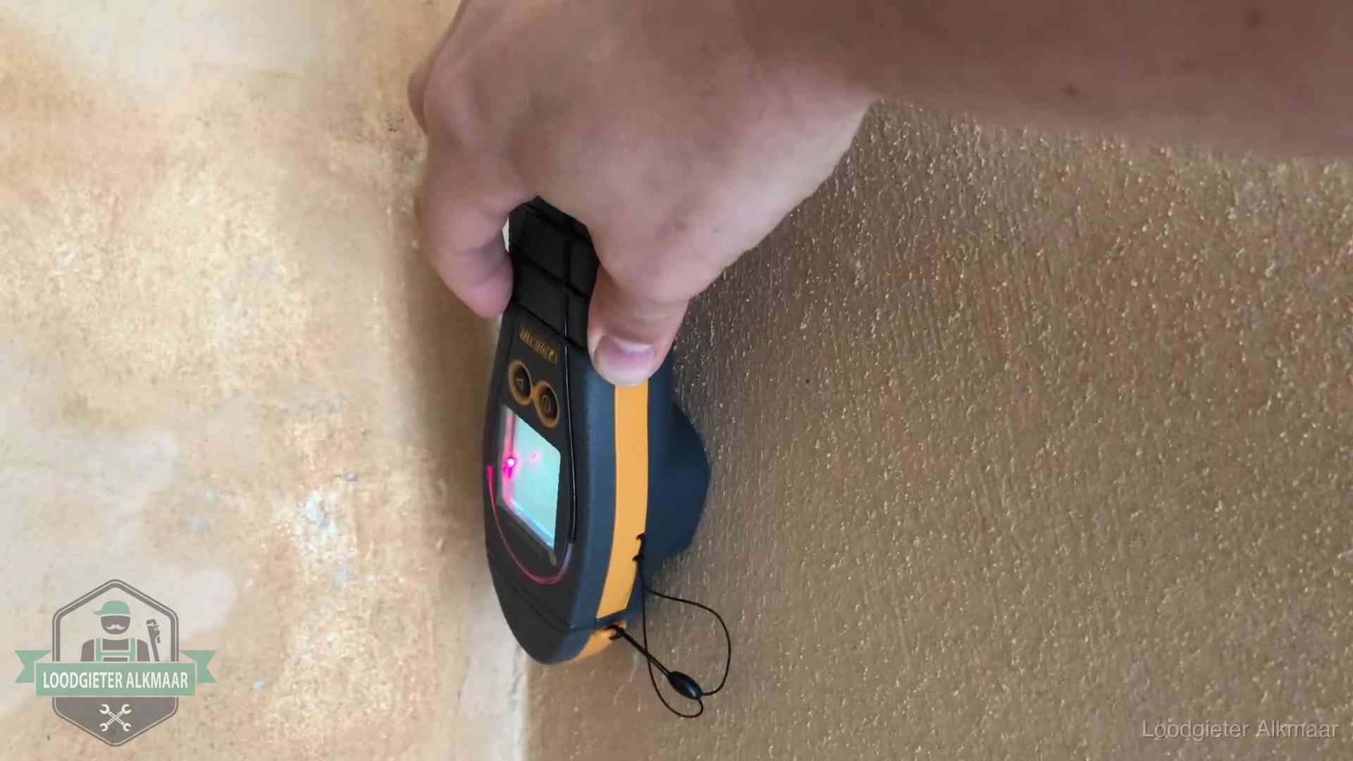 Vochtmeter tegen een muur met vochtplekken tijdens het opsporen van een daklekkage in Alkmaar
