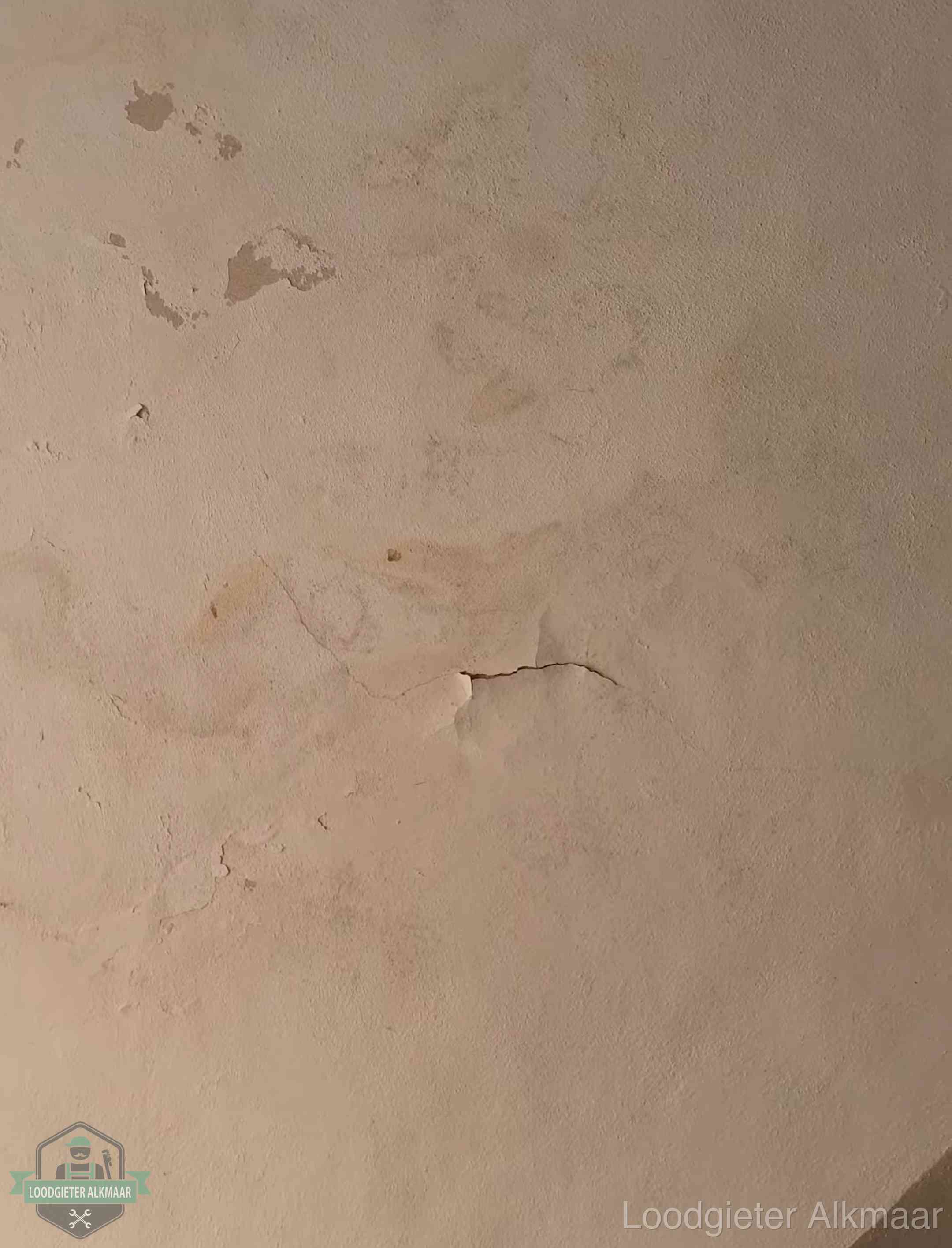 Vochtkringen en afbladderende verf op een plafond in Alkmaar, schade voor het meetrapport en de verzekering